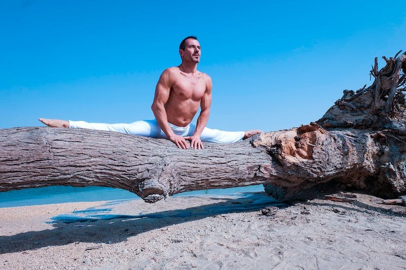 Man doing split on trunk on beach