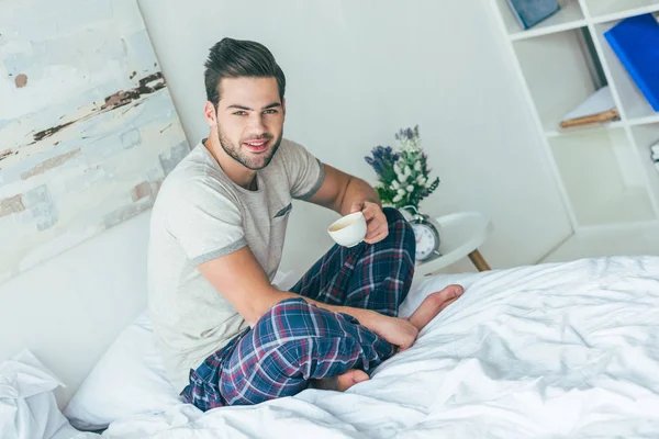 Man drinking coffee on bed
